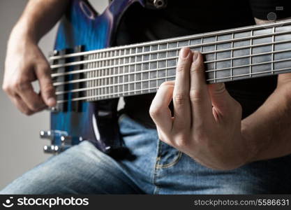 male musician playing on six-string bass guitar