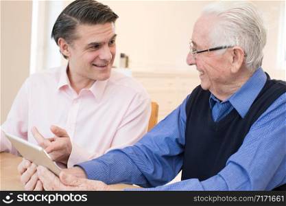 Male Neighbor Showing Senior Man How To Use Digital Tablet
