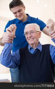 Male Nurse Assessing Senior Stroke Victim By Raising Arms