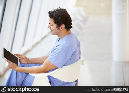 Male Nurse Sitting In Chair Using Digital Tablet