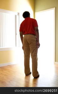 male office worker looking into light filled doorway