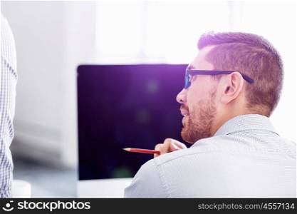 Male office worker sitting at desk. Young businessman sitting at desk in office and holding pen