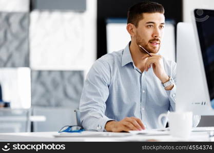 Male office worker sitting at desk. Young businessman sitting at desk in office