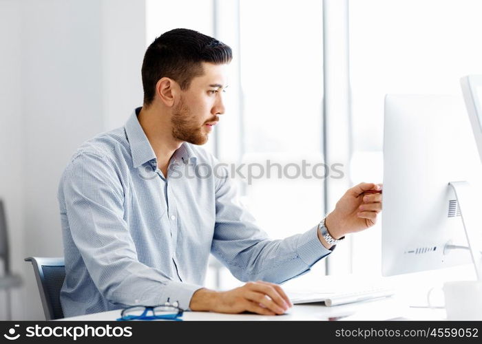 Male office worker sitting at desk. Young businessman sitting at desk in office