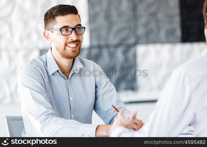 Male office worker sitting at desk. Young businessman sitting at desk in office