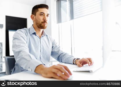 Male office worker sitting at desk. Young businessman sitting at desk in office