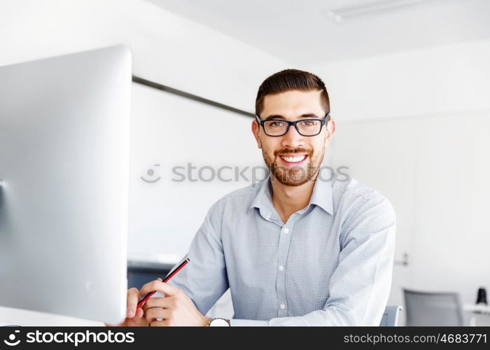 Male office worker sitting at desk. Young businessman sitting at desk in office