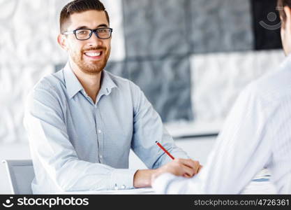 Male office worker sitting at desk. Young businessman sitting at desk in office