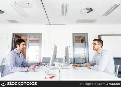 Male office worker sitting at desk. Young businessman sitting at desk in office