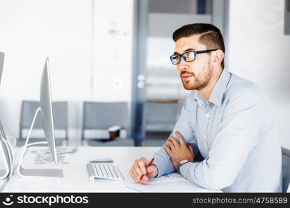 Male office worker sitting at desk. Young businessman sitting at desk in office