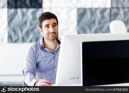 Male office worker sitting at desk. Young businessman sitting at desk in office