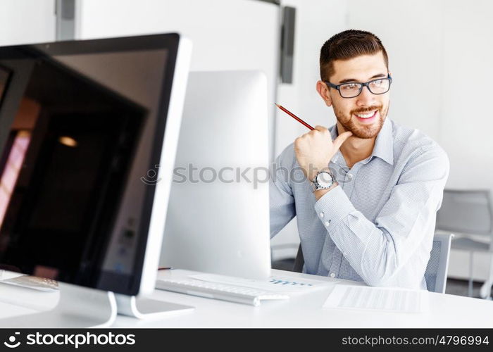 Male office worker sitting at desk. Young businessman sitting at desk in office