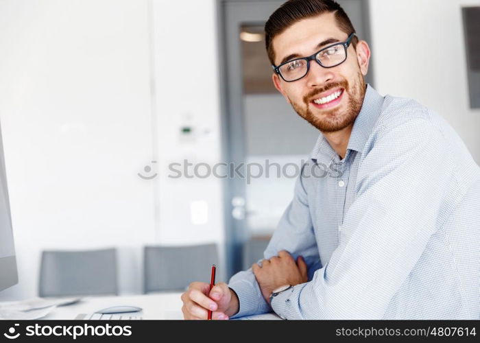 Male office worker sitting at desk. Young businessman sitting at desk in office