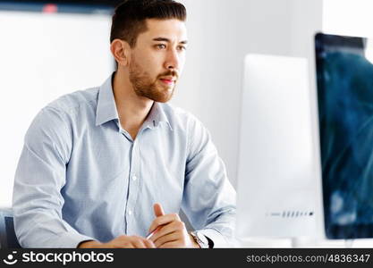 Male office worker sitting at desk. Young businessman sitting at desk in office