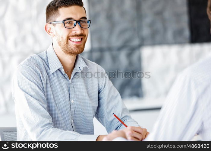 Male office worker sitting at desk. Young businessman sitting at desk in office