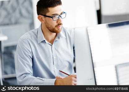 Male office worker sitting at desk. Young businessman sitting at desk in office