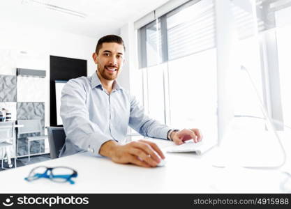 Male office worker sitting at desk. Young businessman sitting at desk in office