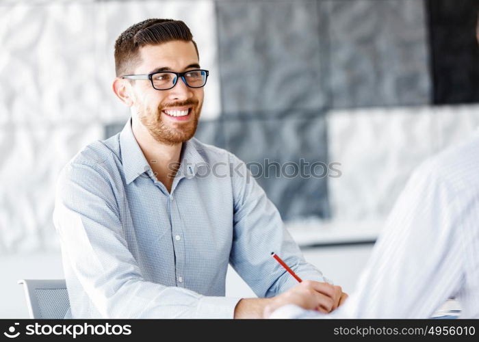 Male office worker sitting at desk. Young businessman sitting at desk in office