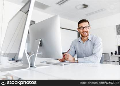 Male office worker sitting at desk. Young businessman sitting at desk in office