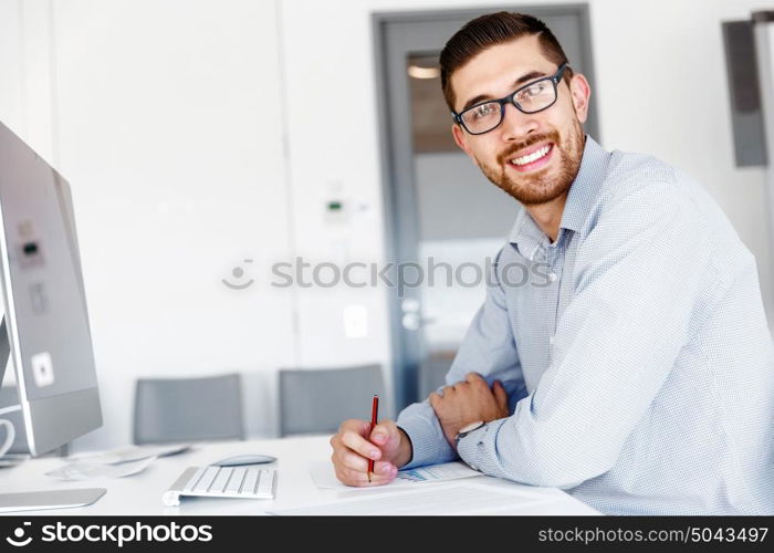 Male office worker sitting at desk. Young businessman sitting at desk in office