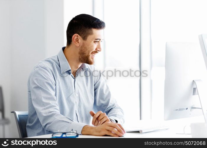 Male office worker sitting at desk. Young businessman sitting at desk in office