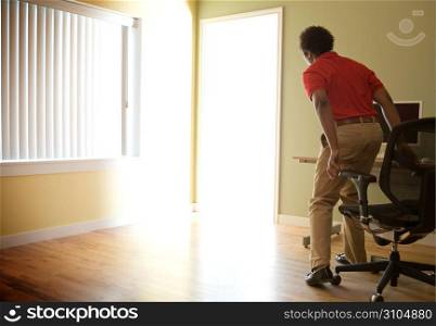 Male office worker standing up from chair to investigate light flooding through doorway
