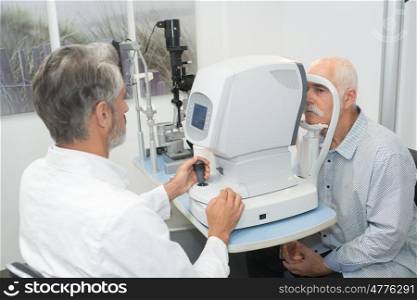 male optometrist doing sight testing for an old patient