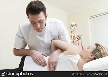 Male Osteopath Treating Female Patient With Back Problem