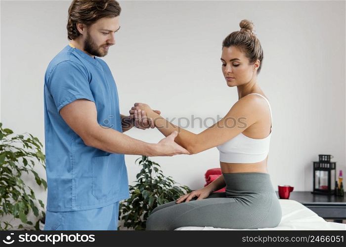 male osteopathic therapist checking female patient s elbow movement