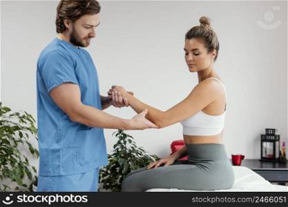 male osteopathic therapist checking female patient s elbow movement