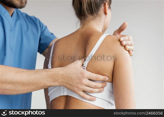 male osteopathic therapist checking female patient s scapula