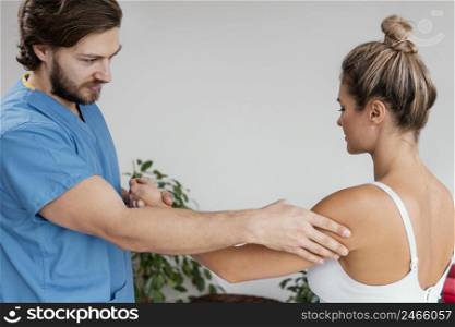 male osteopathic therapist checking female patient s shoulder movement