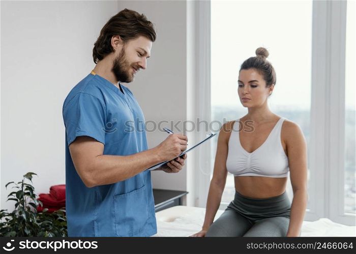 male osteopathic therapist with female patient signing clipboard office