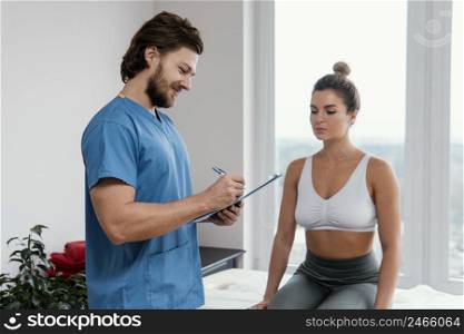 male osteopathic therapist with female patient signing clipboard office