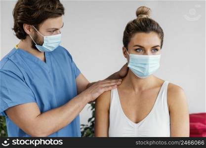 male osteopathic therapist with medical mask checking female patient s neck