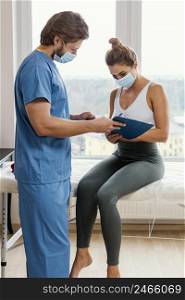 male osteopathic therapist with medical mask patient office signing clipboard