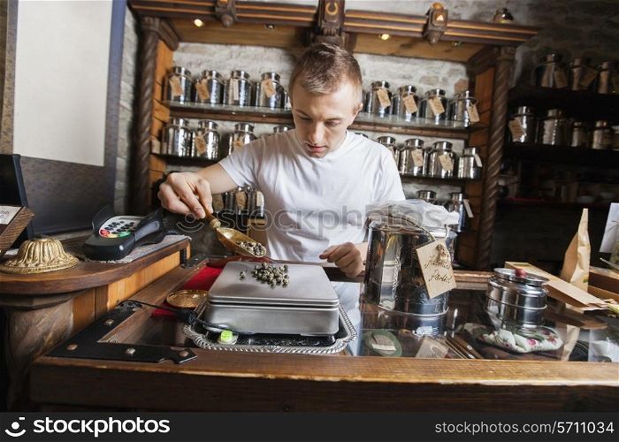 Male owner measuring ingredient on weight scale in tea store