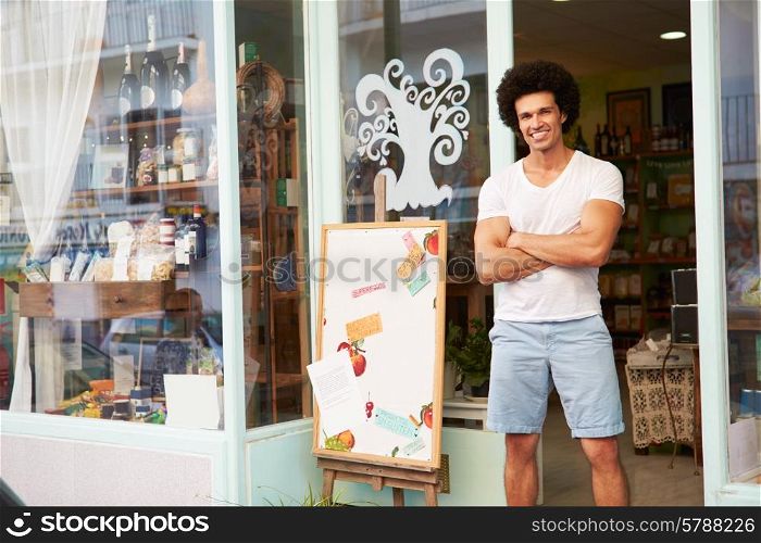 Male Owner Of Delicatessen Standing Outside Shop