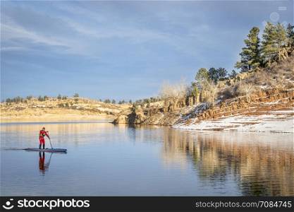 male paddler in a red drysuit enjoying stand up paddling on a mountain lake in Colorado - Horsetooth Reservoir near Fort Collins