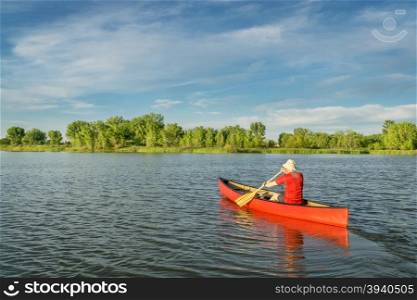 male paddler paddling a red canoe on a local lake in Fort Collins, Colorado