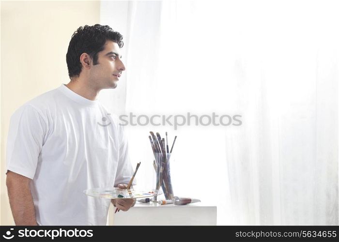 Male painter holding paint palette and brush