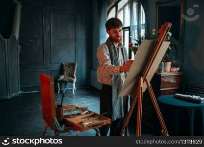 Male painter with brush in hand in front of easel. Oil paint, paintbrush drawing