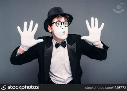Male pantomime actor fun performing. Mime in suit, gloves, glasses, make-up mask and hat. April fools day concept