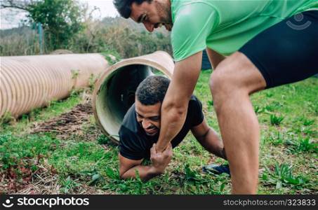 Male participants in an obstacle course going through a pipe. Participants obstacle course going through a pipe