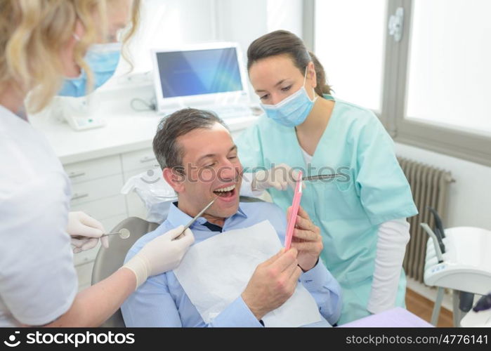 male patient and dentist with assistant during check up