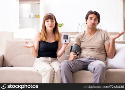 Male patient getting treatment at home. Wife checking husband&rsquo;s blood pressure 