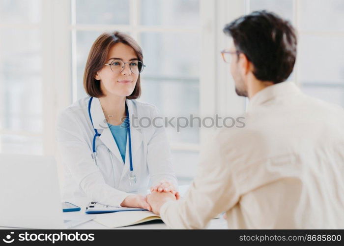 Male patient has consultation with female doctor, receives support, finds out about serious disease. Woman therapist comforts ill visitor in office or consulting room, talk about how to cure illness