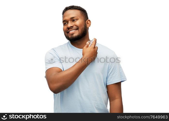 male perfumery, grooming and people concept - happy smiling young african american man with perfume over white background. happy african american man with perfume
