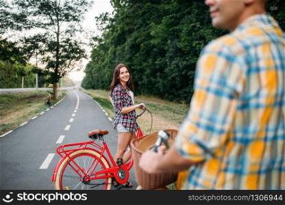 Male person and young woman riding on retro bikes. Couple on vintage bicycles. Young man and woman on old cycles, romantic date
