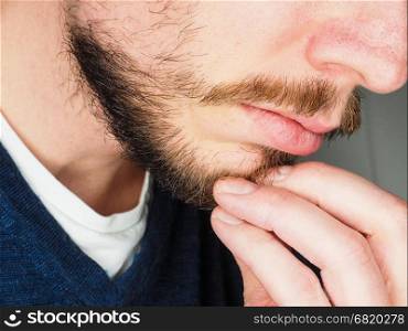 Male person, at closeup with fingers in beard